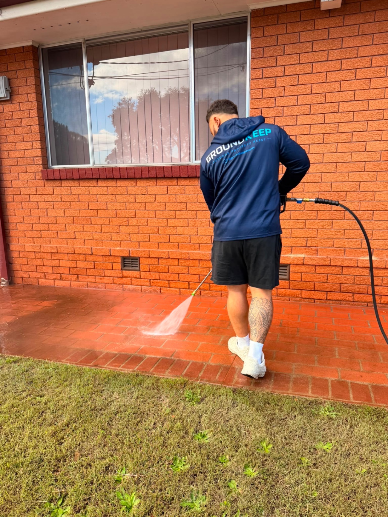 GroundKeep pressure washing a red brick wall and paved edge in South West Sydney